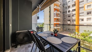 A balcony with a table, chairs, and an air conditioning unit. - Kiti Apartment Beach Escape (Vlorë)