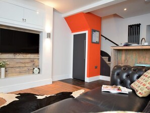 Un salon moderne avec une cheminée, un canapé en cuir et un tapis en peau de vache.