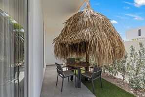 A balcony with a thatched umbrella, a round table, and two chairs. - Apartment Sunset Vista A - 2 pers with pool at Jan Thiel (Jan Thiel)