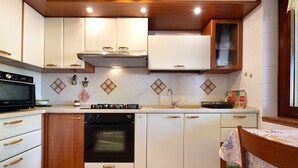 Uma cozinha com armários brancos, forno embutido, micro-ondas e pia.