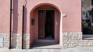 Entrada de um edif ício com base de pedra, parede rosa e porta de madeira.