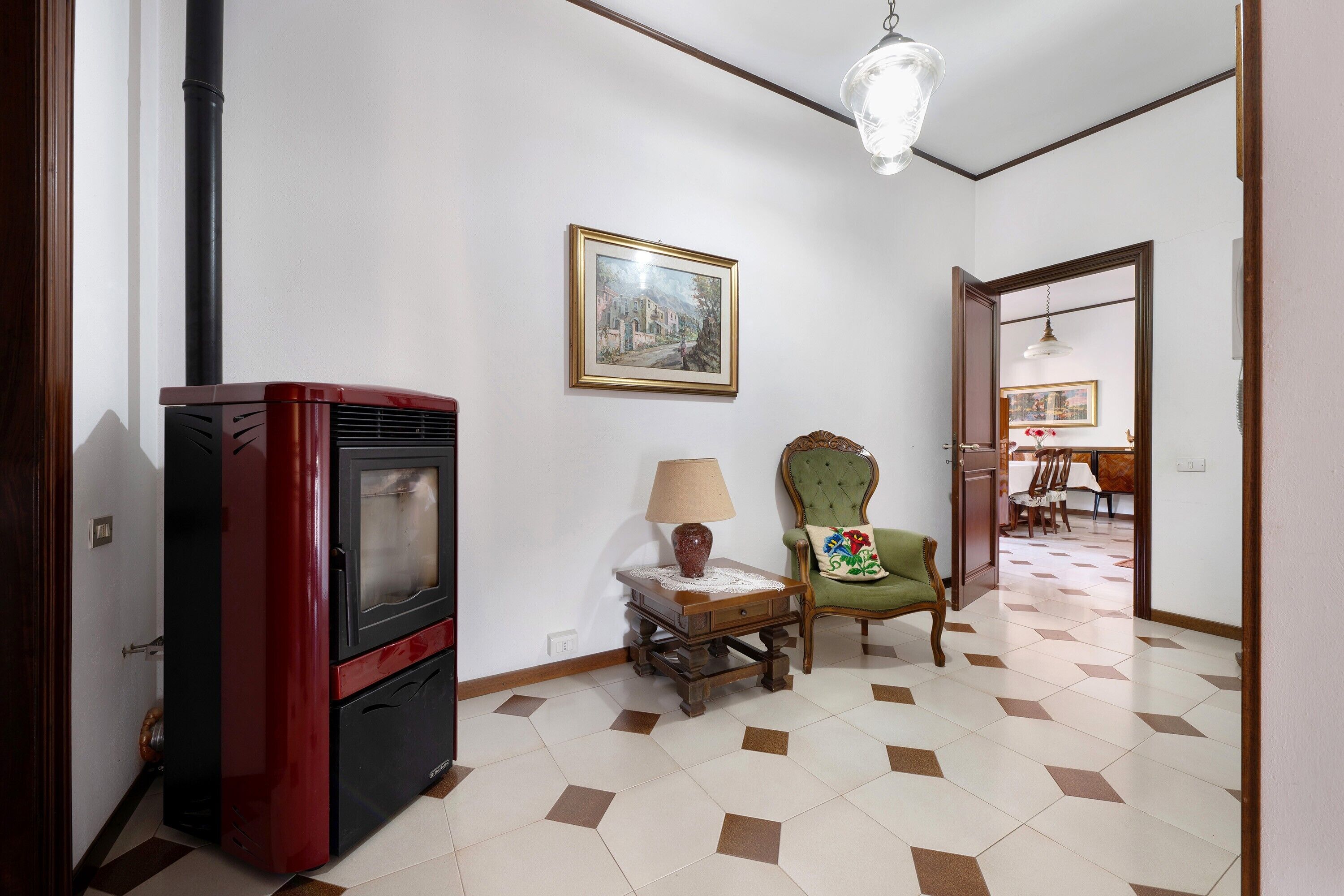 Une pièce avec un téléviseur ancien, une lampe, une chaise et un tableau encadré accroché au mur.