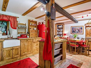 Eine rustikale Küche mit Holzausstattung, einem roten Kühlschrank und einem Essbereich mit roten Stühlen.
