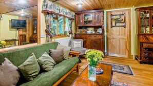 Uma sala de estar acolhedora, com um sofá verde, armários de madeira e uma televisão.