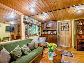 Ein gemütliches Wohnzimmer mit einem grünen Sofa, Holzschränken und einem Fernseher.