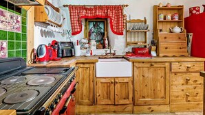 Uma cozinha com armários de madeira, fogão a gás, cafeteira e diversos utensílios de cozinha.