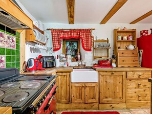 Eine Küche mit Holzschränken, einem Gasherd, einer Kaffeemaschine und diversen Küchengeräten.