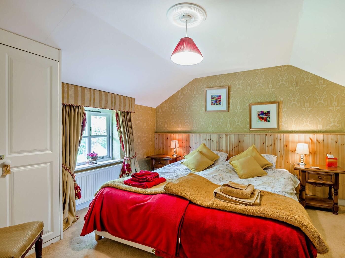 Une chambre à coucher comprenant un lit, deux tables de chevet, une fenêtre avec des rideaux, un radiateur et une porte.