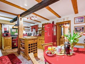 Eine gemütliche Küche mit Holzbalken, einem roten Kühlschrank und einem Frühstückstisch mit roter Tischdecke.