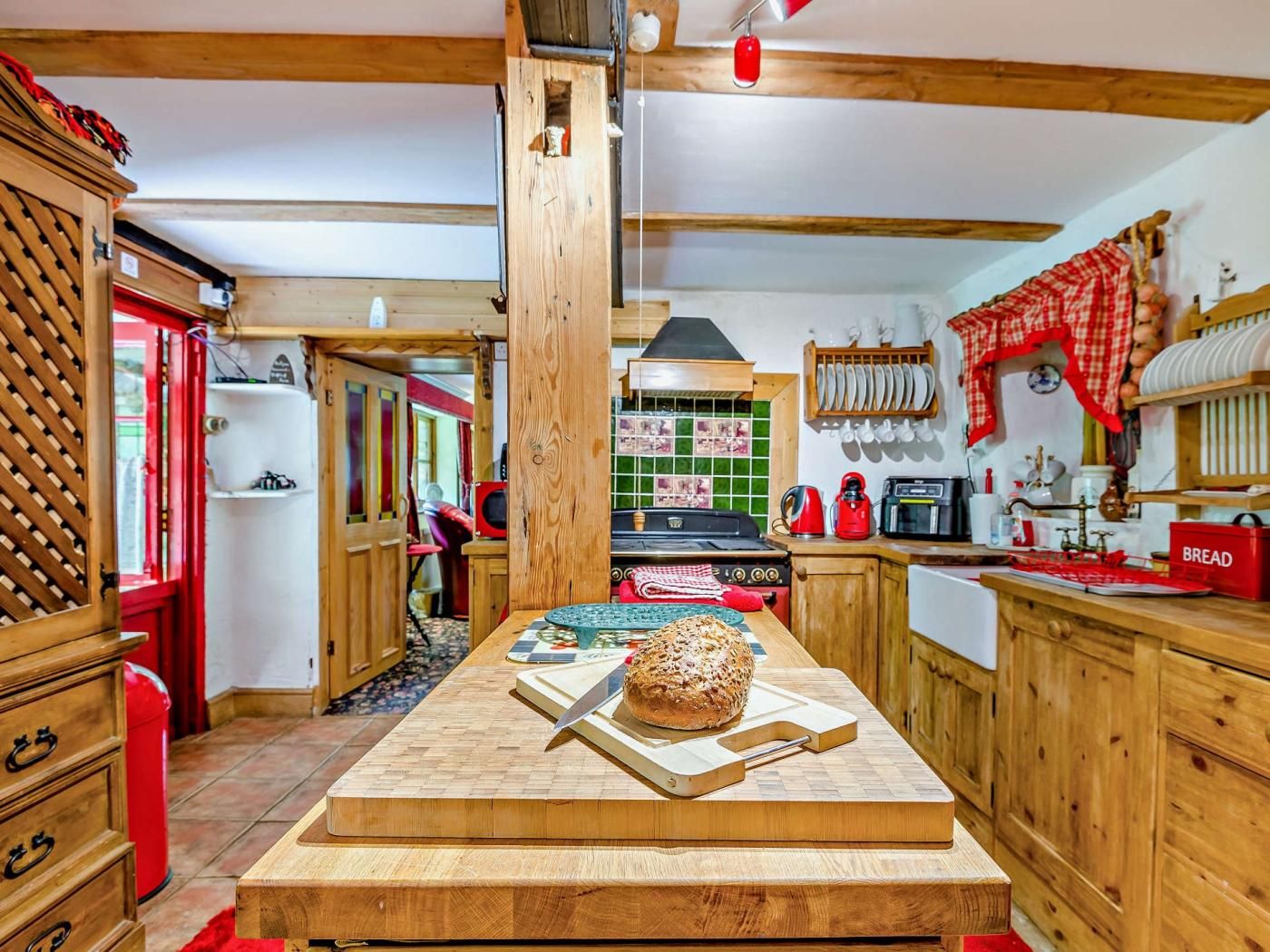A kitchen with wooden cabinets, a central island, and a red and white checkered cloth hanging on the wall.