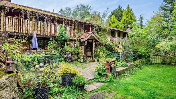 Uma casa rústica com jardim, cerca de madeira e área de estar ao ar livre.