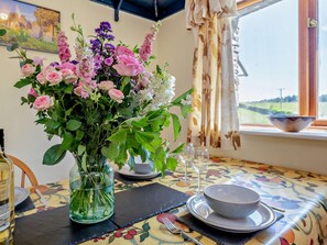 Ett matbord med en blomsterdekoration i mitten, en skål och vinglas.