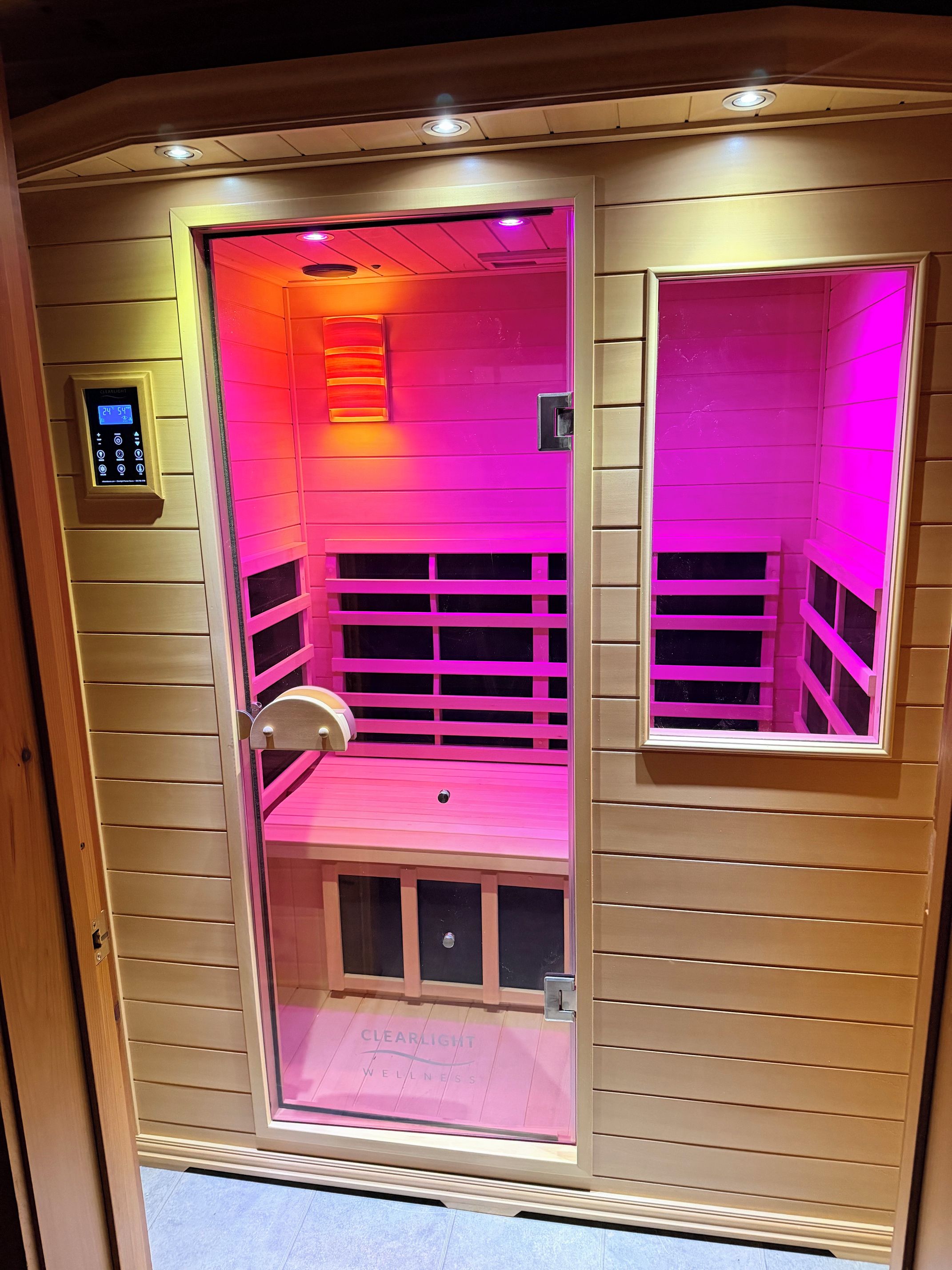 Una sauna con pannello di controllo, una panca e una finestra.