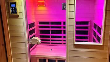 Una sauna con pannello di controllo, una panca e una finestra.