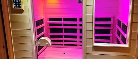 A sauna with a control panel, a bench, and a window.