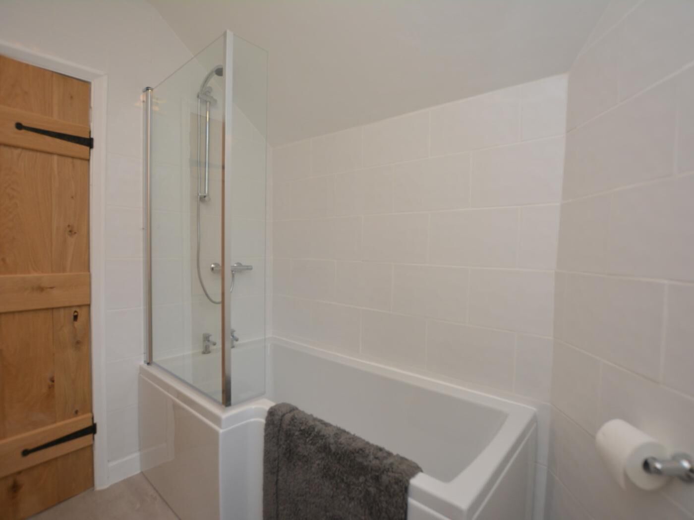 A bathroom with a glass-enclosed shower, a bathtub, and a wooden door.