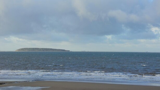 A beach with a distant island and overcast sky. - 2 Bed in Penmaenmawr (oc-56081) (Penmaenmawr)