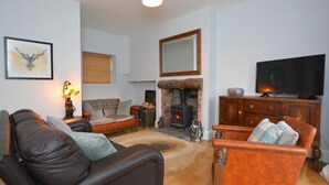 A living room with a fireplace, a television, and a sofa. - 2 Bed in Penmaenmawr (oc-56081) (Penmaenmawr)