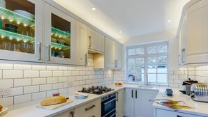 A modern kitchen with white cabinetry, a gas stove, an oven, and a window with a view. - 3 Bed in Whitstable (oc-wcc12) (Whitstable)