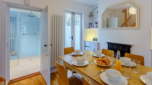 A dining area with a table set for four, a fireplace, and a large mirror above the mantel. - 3 Bed in Whitstable (oc-wcc12) (Whitstable)