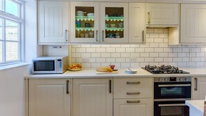 A kitchen with white cabinets, a microwave, a gas stove, and an oven. - 3 Bed in Whitstable (oc-wcc12) (Whitstable)