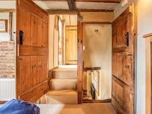 A wooden interior with a staircase leading to a door with a heart-shaped decoration.