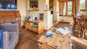 Una habitación acogedora con un escritorio de madera, televisor y comedor con mobiliario de madera.