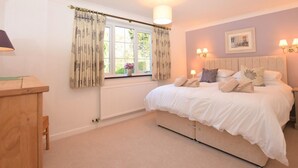 A bedroom with a bed, a window with curtains, a bedside table, and wall-mounted lights. - 3 Bed in Dereham (oc-56661) (Horningtoft)
