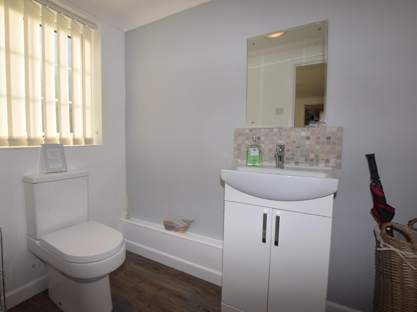 A bathroom with a toilet, a white sink with a mirror above it, and a bathtub.