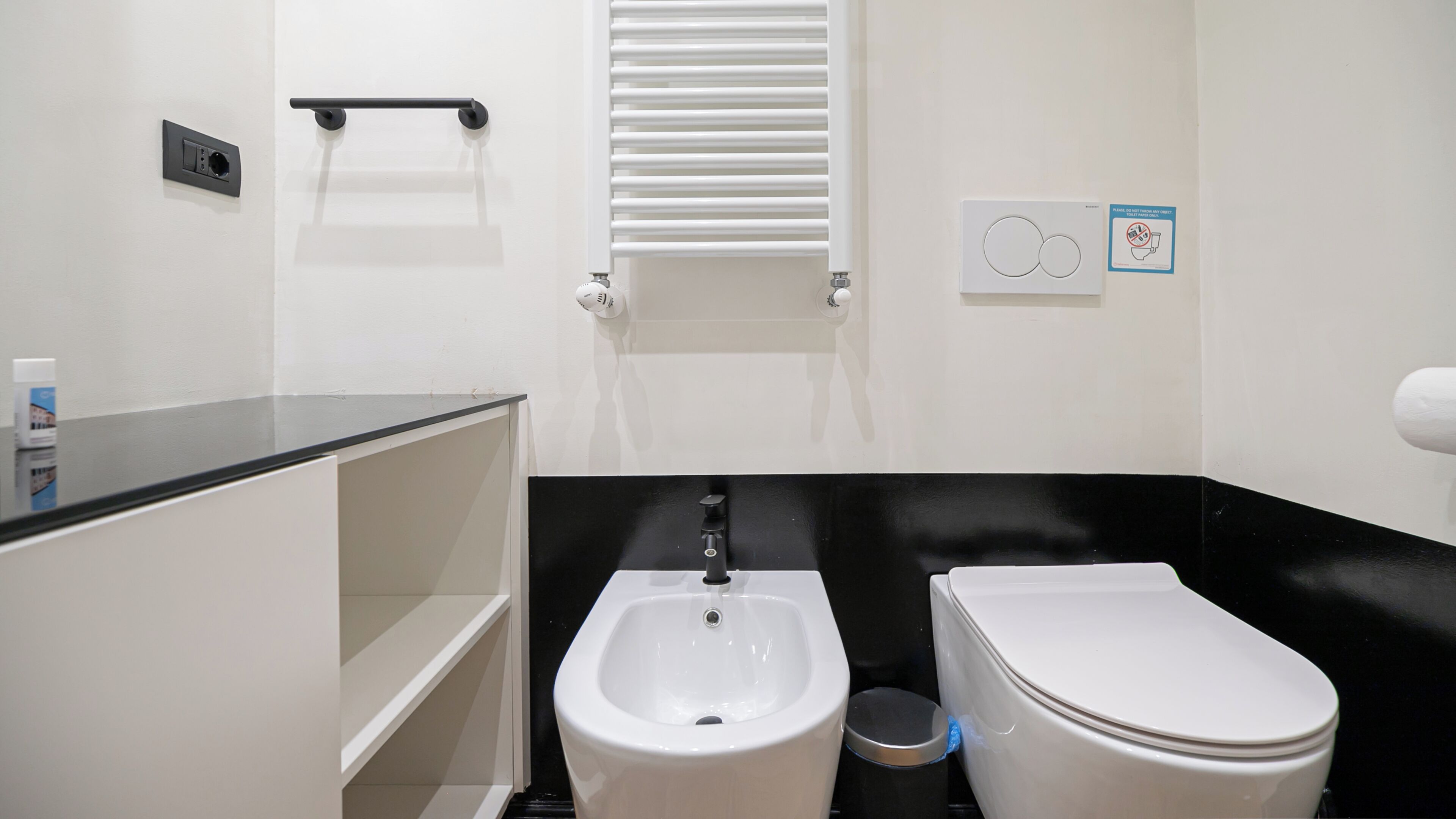 Un baño con bidé, inodoro, perchero para toallas y secamanos.