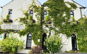 A building with a sign reading 'LIFTON KITCHEN & HOLIDAY APARTMENTS.' - Alway at Lifton Hall (Lifton)