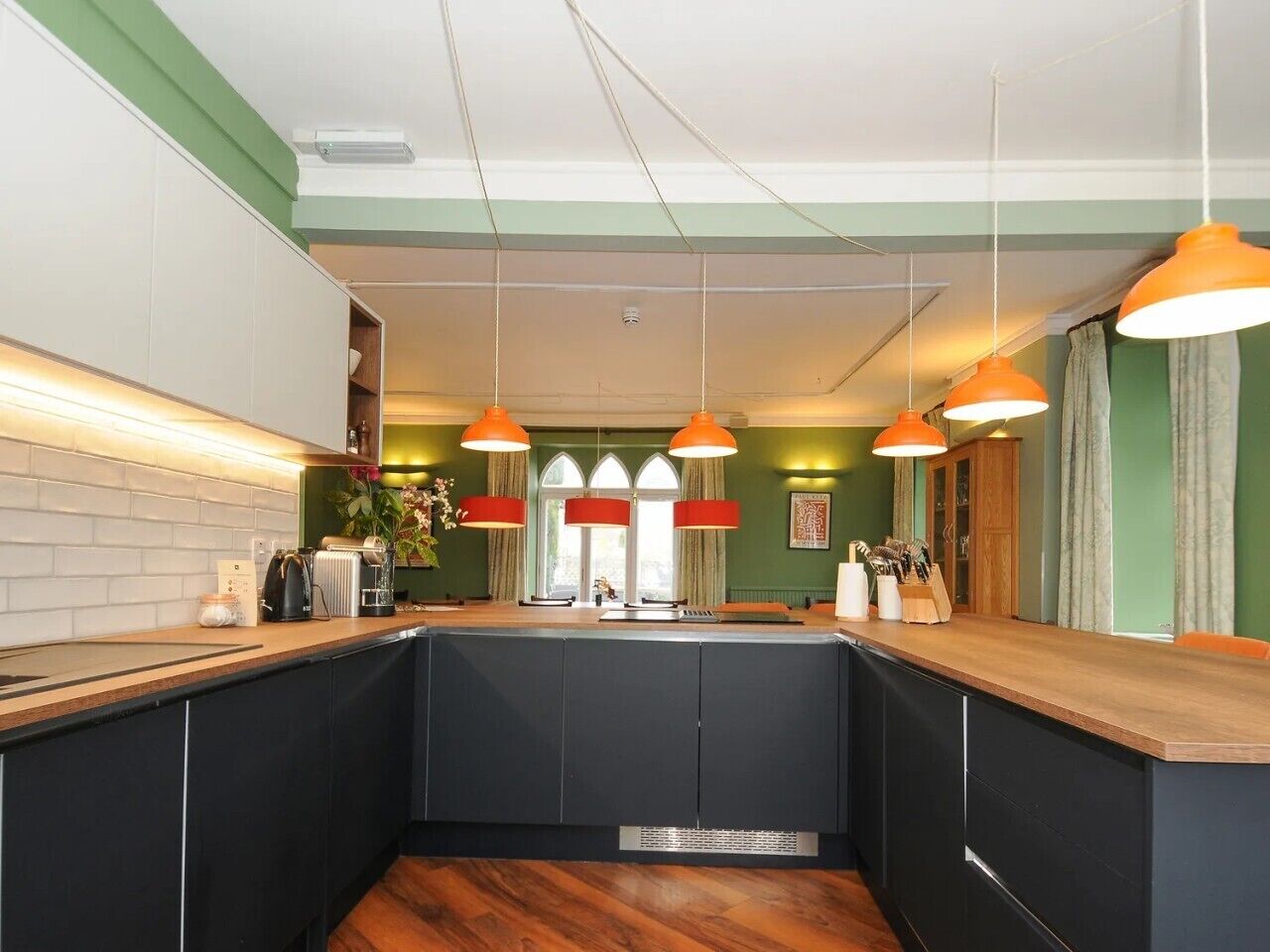 A kitchen with a central island, pendant lighting, and a view of the dining area.
