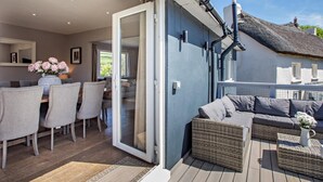 A cozy room with a dining table, chairs, a sofa, and a wicker bench. - 4 Bed in Braunton (oc-56111) (Croyde)