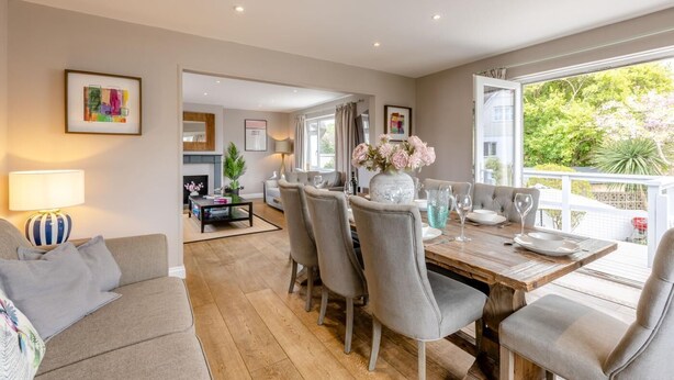 A dining area with a wooden table, grey upholstered chairs, and a vase of flowers. - 4 Bed in Braunton (oc-56111) (Croyde)