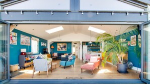 Um interior moderno com sala de estar, cozinha e espaço para refeições, destacando uma janela ampla e um vaso com planta.