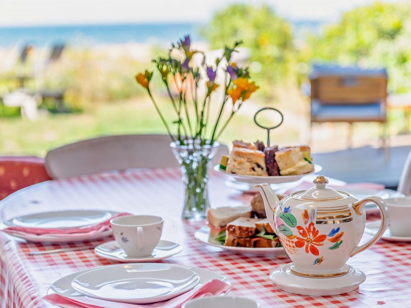 Une table dressée pour le thé, avec une théière, des tasses et un présentoir à gâteaux à plusieurs niveaux.