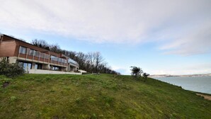 Un edificio moderno con amplios ventanales, techo plano y un área verde frontal.