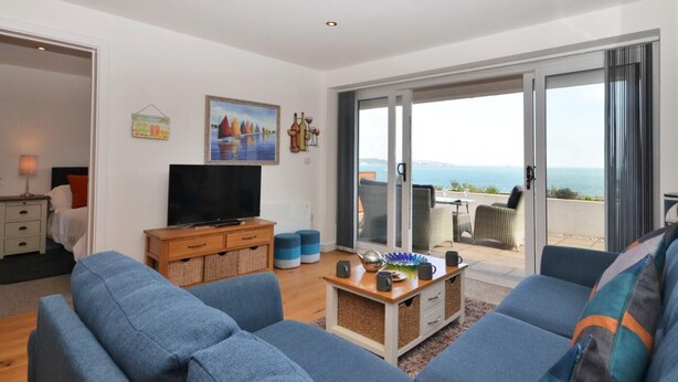 Una sala moderna con un conjunto de sofá, televisor y comedor con mobiliario de exterior.