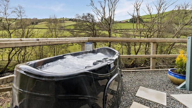Een hottub op een terras met uitzicht op een groen landschap.