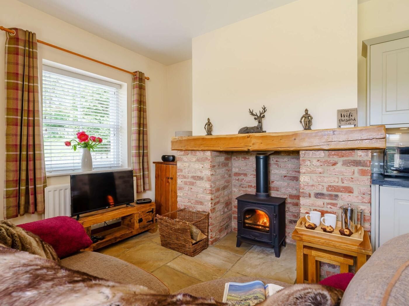 Una sala de estar acogedora con chimenea, televisor y ventana con cortinas.