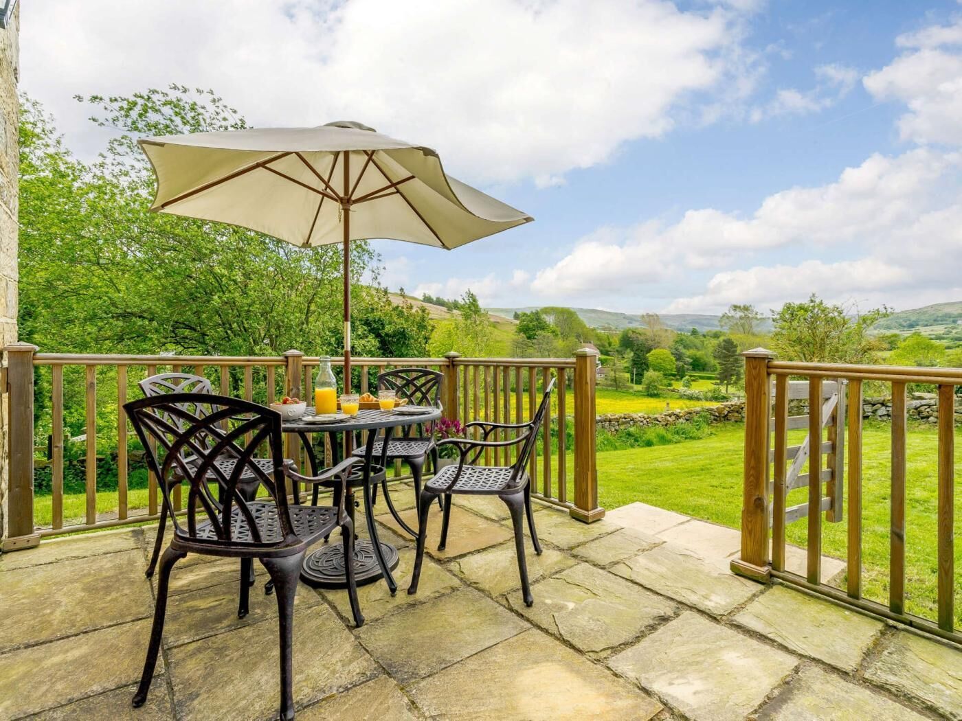 A patio with a table, chairs, and a large umbrella.