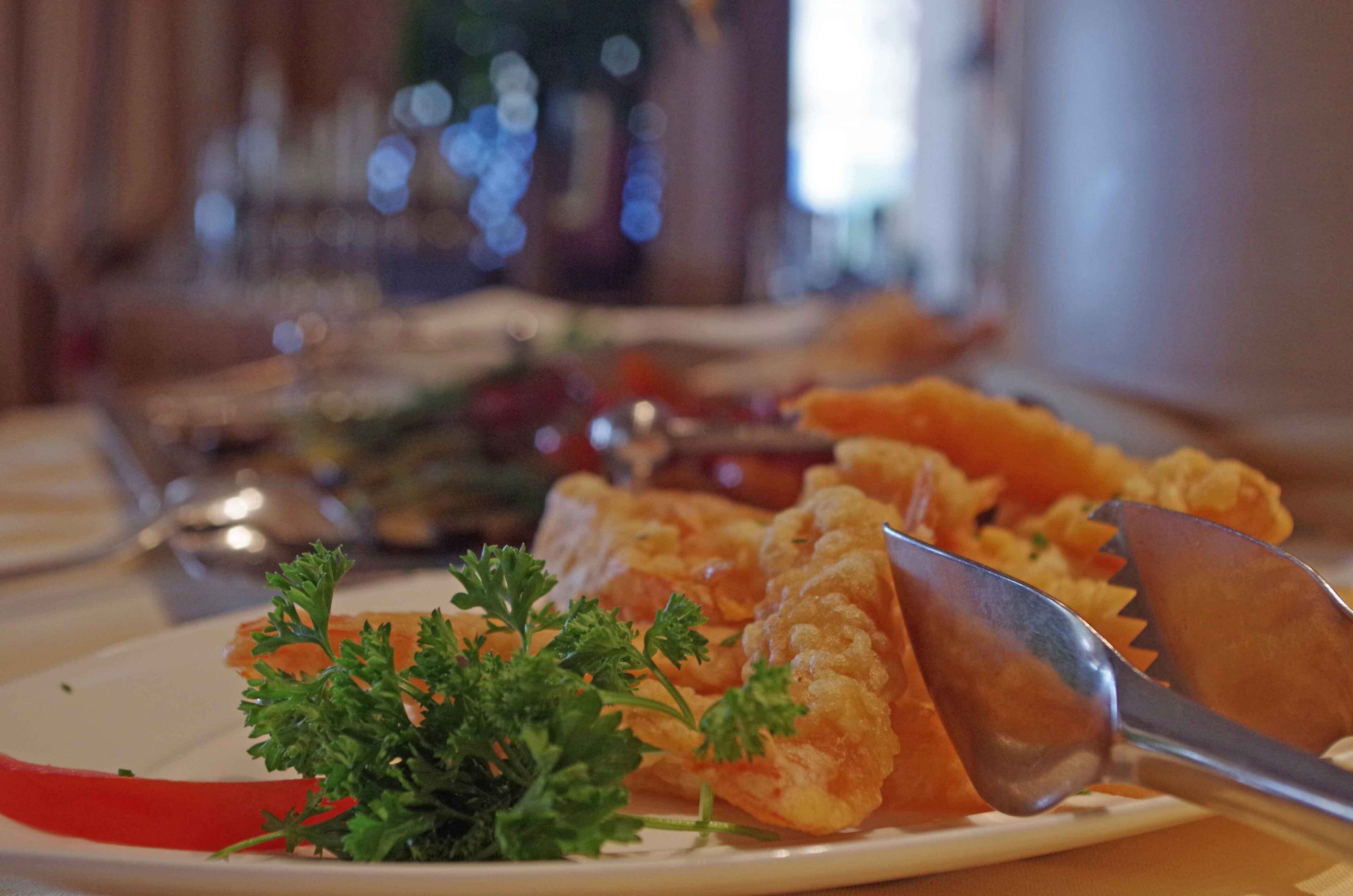 A dining table with plates of food, utensils, and a glass of water.