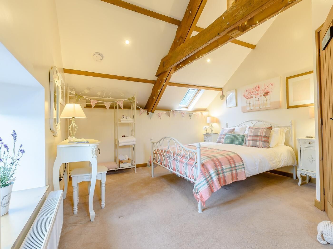 A bedroom with a bed, bedside tables, a desk, a radiator, and a window.