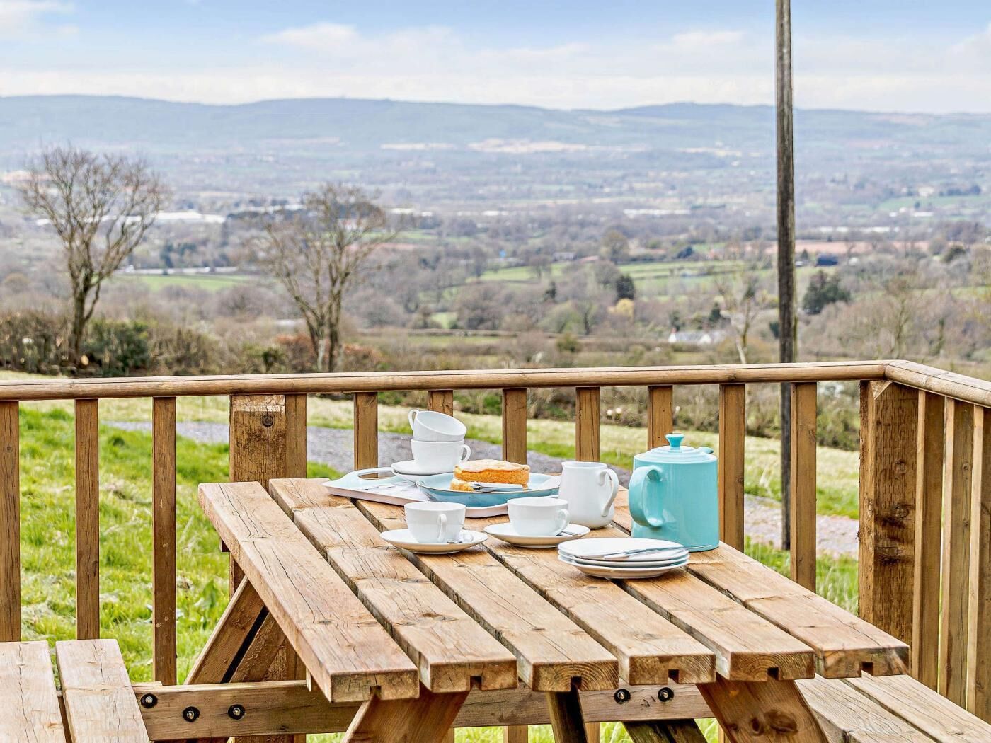 Un tavolo da picnic in legno con vista su un paesaggio rurale.