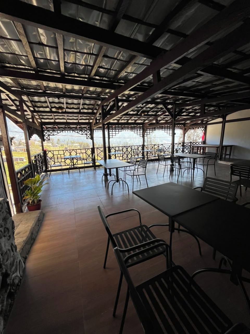 An outdoor patio with tables and chairs, a pergola structure, and a view of the landscape.