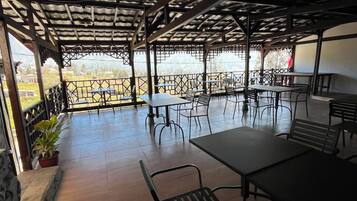 An outdoor patio with tables and chairs, a pergola structure, and a view of the landscape.