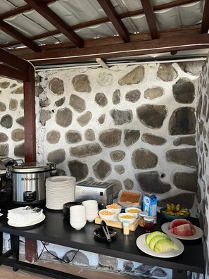 A stone wall with a metal stove and various food items on a table.