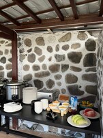 A stone wall with a metal stove and various food items on a table.