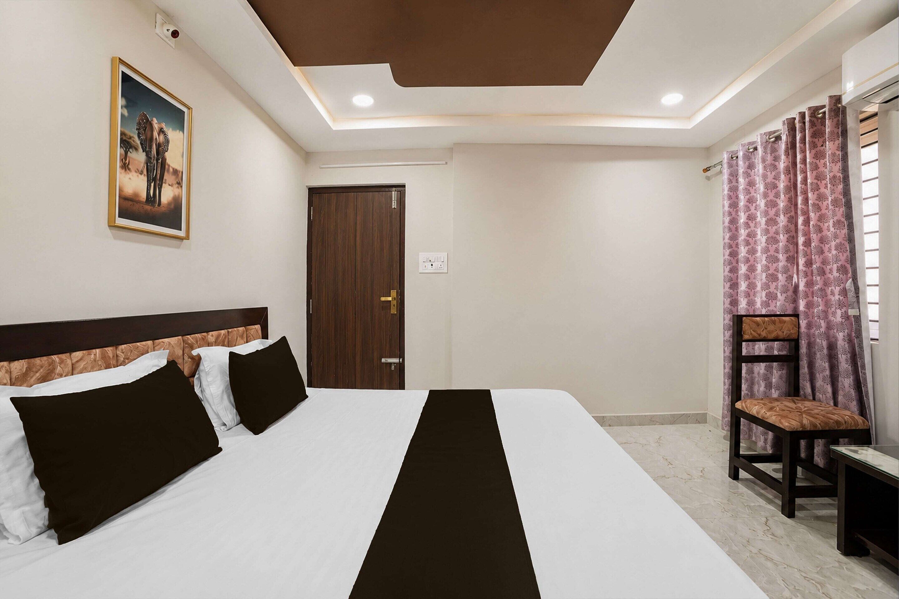 Une chambre d’hôtel avec un lit, une chaise, une porte et un tableau au mur.