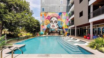 A swimming pool with a mural, a 4 ft no diving sign, and a building with balconies.
